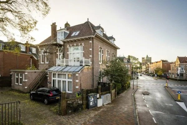 Hoekpand met trapgevel aan de Van Eedenstraat, met geparkeerde auto en zicht op een rustige straat in een historische woonwijk.